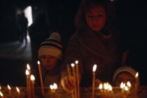 Woman and child lighting candles inside church on Christmas day.Etchmiadzin Armenian Asia Asian European Kids Middle East Religion Religious Xmas Children Female Women Girl Lady Female Woman Girl Lad...