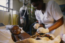 Nurse attending critically ill child in malaria research unit. African Children Eastern Africa Kenyan Kids