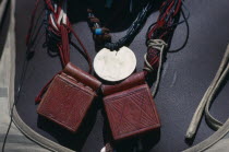 Close view of leather pouches containing verses of the Koran worn as a charm around the neck by Chadian refugee woman together with old French coin and beads.