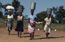 Group of women carrying water vessels on their heads.