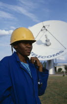 Portrait of station supervisor of telecommunications company standing in front of satelite dish.