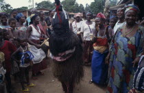 Female initiation ceremony with masked initiate amongst a group of women and children