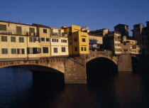 Ponte Vecchio  the west side in warm  golden light with people standing on central section.  Firenze Italia Italian Southern Europe European Toscana Tuscan