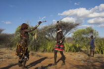 Hama Jumping of the Bulls initiation ceremony. Man whipping women on back in ritual flogging   The whip is made of rope or reed bushes