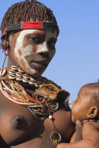 Karo woman with face painting  breast feeding baby.