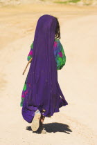 Kuchie nomad girl walking behind camel train