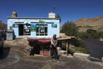 Between Kabul and Bamiyan  after Hejigak pass  Man hoseing road infront of his chiakana  tea house  to stop the dust blowing in