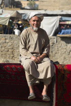 Rug seller sit on walls of Kabul river