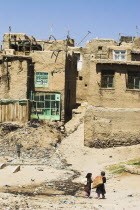 Children walk with sacks over their shoulders toward houses inside the ancient walls of Citadel  The citadel was destroyed during First Anglo Afghan war since rebuilt still used as a military garrison