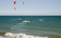 Kite Surfers on sea next to beach in the summer with blue sky