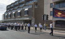 The Salvation Army Band marching along seafront with flags flying in the summer.