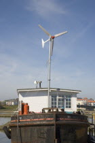 Houseboat  with large wind turbine in the deck  moored along the banks of the river adur. Wind turbine to generate electricity for the vessel.