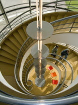 The De La Warr Pavilion. Interior view down the helix  staircase with chrome Bauhaus globe lamps. Visitors walking the stairs. Three colourful chairs seen at the bottom.European Great Britain Norther...