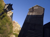 Black wooden huts used for storing fishing nets.The East Hill Lift funicular railway behind.