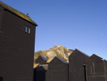 Black wooden huts used for storing fishing nets.The East Hill Lift funicular railway behind.