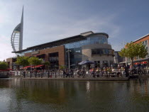 Gunwharf Quays complex. View across water towards restaurants  bars and shopping outlets. Spinnaker Tower behind.