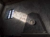 Boxgrove Priory Church of St Mary and St Blaise. Interior view of  light shining through small window onto a wall and marble monument.