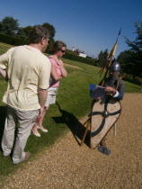 Battle Abbey. Visitors in grounds of partially ruined abbey complex  talking to a foot soldier near to the spot that King Harold fell in the 1066 Battle of Hastings