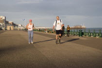 Woman jogging with man rollerblading on the seafront promenade.European Great Britain Northern Europe UK United Kingdom British Isles