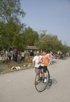 Amberley Working Museum. Veteran Cycle Day Grand Parade. Young Boy riding a small version Penny Farthing bicycle with visitors watching.