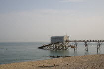 Royal National Lifeboat Institution. View across shingle beach towards a pier with RNLI station