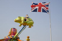 Families enjoying amusement ride at Harbour Park. British Union Jack flag Flying against a blue sky