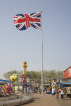 Harbour Park Amusements with families enjoying rides.  British Union Jack flag flying in the wind against a blue sky
