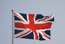British Union Jack flag flying in the wind against a blue sky