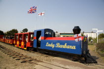 Families enjoying a miniature railway ride in Norfolk Gardens with Union Jack Flag flying behind.