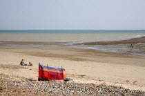 View towards the sea from beach with sunbathers behind colourful wind break on sand