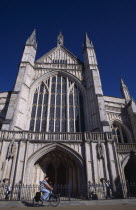 Winchester Cathedral exterior with a man travelling past on a bicycle