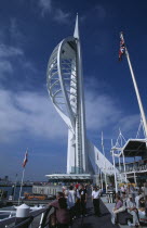 Gunwharf Quay, The Spinnaker Tower with people on the waterfront promenade looking out across the marina