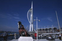 Gunwharf Quay, Spinnaker Tower with figurehead in the foreground. People on the waterfront promenade viewing the harbour.