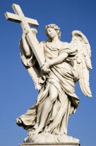White marble statue of a winged female angel holding a cross on the Ponte Sant Angelo bridge with a clear blue sky