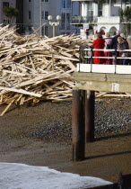 Timber washed up on the beach from the Greek registered Ice Princess which sank off the Dorset coast on 15th January 2008. Sightseers on the pier look at the debris beside it