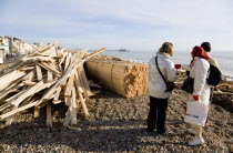 Timber washed up on the beach from the Greek registered Ice Princess which sank off the Dorset coast on 15th January 2008. Three people stand amongst the debris with Worthing Pier in the distance