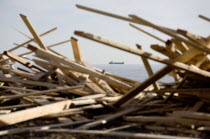 Timber washed up on the beach from the Greek registered Ice Princess which sank off the Dorset coast on 15th January 2008. A cargo ship passes in the distance on the horizon