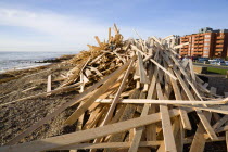 Timber washed up on the beach from the Greek registered Ice Princess which sank off the Dorset coast on 15th January 2008. People walk on the promenade with seafront buildings beyond