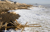 Timber washed up on the beach from the Greek registered Ice Princess which sank off the Dorset coast on 15th January 2008. People walking past waves crashing against the shoreline