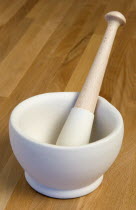 White ceramic pestle and mortar on a wooden kitchen surafce worktop