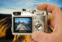 Digital camera held in a hand with an image on the screen and in the background of Monument Vally  studio shot with camera held in front of a print