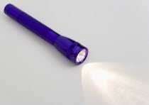 Purple magilite torch turned on and casting a beam of light over a white surface
