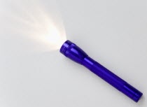 Purple magilite torch turned on and casting a beam of light over a white surface