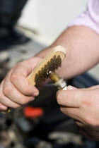 Man cleaning a sparkplug with a wire brush