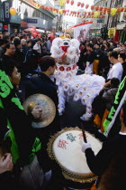 Lion Dance troupe performing in Wardour Street amongst the crowd outside restaurants during Chinese New Year celebrations in 2006 for the coming Year of The Dog