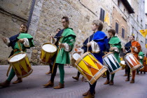 ITALY, Tuscany, San Gimignano, Boys and young men in Medieval costume beating drums in a parade through the streets during a pageant in the town.