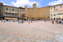ITALY, Tuscany, Siena, People walking in the Piazza del Campo past the Palazzi and restaurants that border the square.