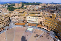 ITALY, Tuscany, Siena, Skyline cityscape over the Piazza del Campo and the north of the city. People walk in the square past the Palazzi and restaurants that border it.