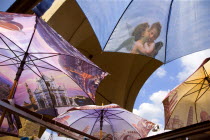 ITALY, Tuscany, Florence, Brightly coloured umbrellas for sale on the Ponte Vecchio with images of Florence and cherubs on them.