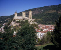 Chateau Foix on hilltop above town with tree covered hillside beyond.  Built on 7th C. fortification and known to date from the 10th C.  now houses the Musee d Ariege.